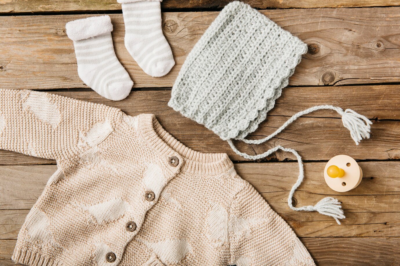 Freepik Overhead View Woolen Baby S Clothing With Pacifier Wooden Table_23 2147900741